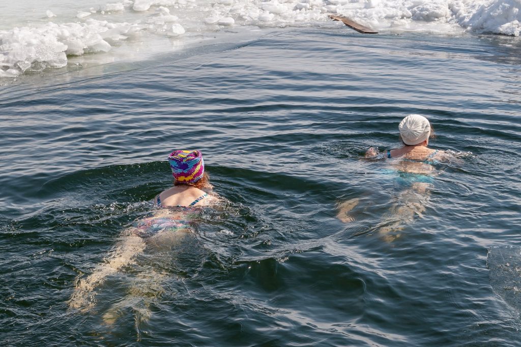 dwie morsujące osoby pływają w zimnej wodzie